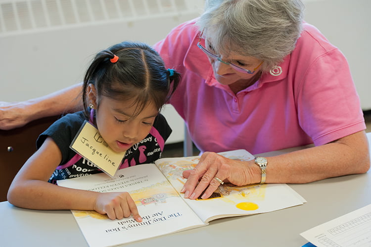 Mary Zeller, a member of Guardian Angels Parish in Kansas City, Mo., helps Jacqueline Gutierrez, 6, with reading at The Learning Club. The Learning Club offers students in the poorest part of the city tutoring and a consistent support system.