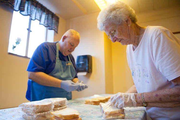 Larry Lesser, a member of Sacred Heart Parish in Topeka, and Mary Kirk, a member of Mater Dei Parish in Topeka, prepare the day’s sandwiches. The ministry typically hands out more than 100 sandwiches a day. 