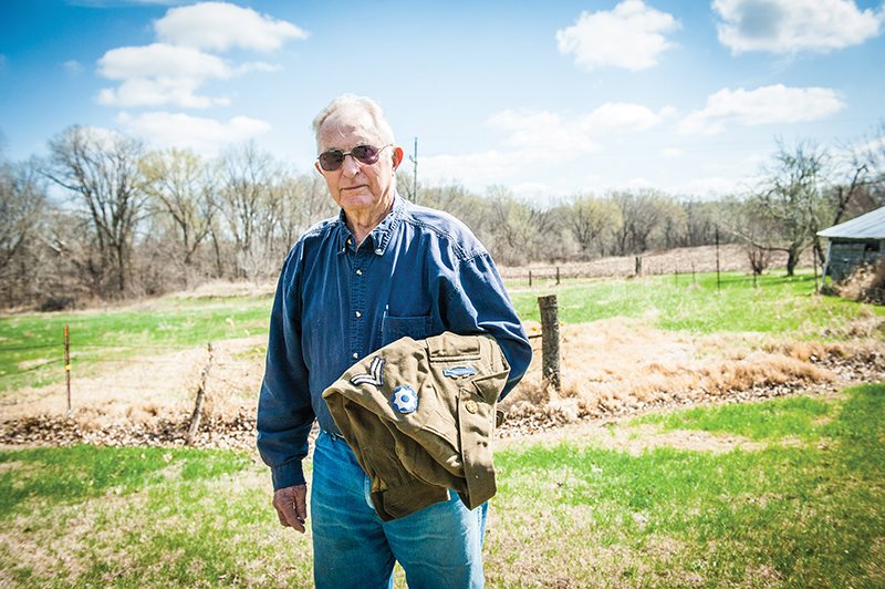 At 91, Siebert is still the picture of health. He continues to live in the farmhouse his father built and raises cattle. Here, he holds with his Army uniform from World War II.  