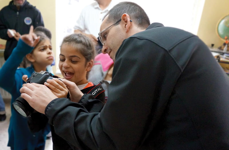 While visiting an orphanage in Jerusalem, Deacon Dan Morris shows a little girl the photos he has taken.  