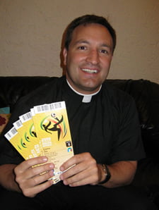 Father Mitchel proudly displays his World Cup tickets — tickets that took him almost two years to get.