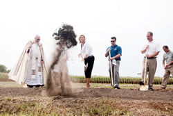 Shelly Buhler, chair of the St. Stanislaus building committee, throws dirt during the groundbreaking ceremony as Archbishop Joseph F. Naumann looks on. To Buhler’s left are David Heit, architect at the Schwerdt Design Group, and Pat Tolin, project manager at Ferrell Construction.