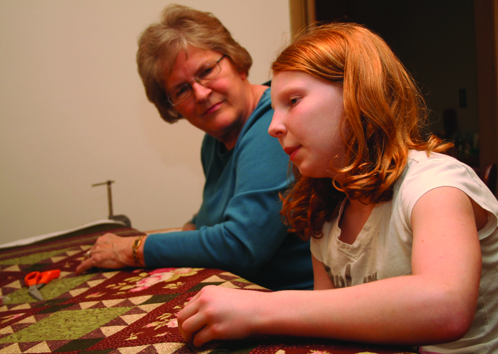 Penny Zweimiller, a member of St. Joseph Parish, Flush, teaches her 11-year-old granddaughter Jana Kellogg how to quilt. For nearly 100 years, quilters from St. Joseph have been building quilts to be raffled at the parish’s annual picnic.