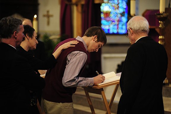 Joe Levinson, 18, a member of Holy Angels Parish in Basehor, signs the Book of the Elect at the Rite of Election on Feb. 24 at the Cathedral of St. Peter in Kansas City, Kan. Photo by Elaina Cochran. 