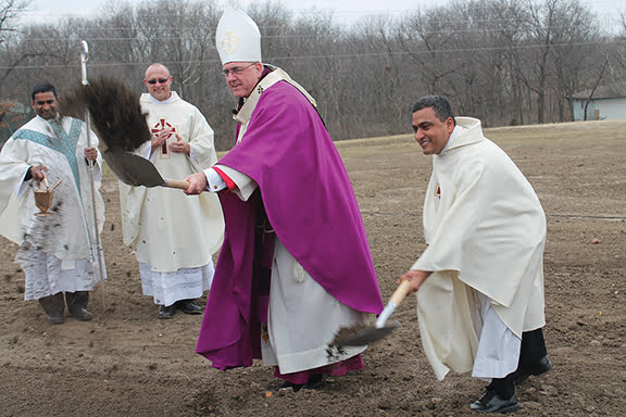 Archbishop Joseph F. Naumann and Father Tom Aduri, pastor of Mother Teresa Parish in Topeka, toss the first shovelfuls of dirt on March 16 to break ground on the Family Formation Center. Father Lourdu Marreddy Yeruva (far left), the parochial administrator of nearby St. Theresa Parish in Perry, and Father Bill Bruning, Mother Teresa’s founding pastor (second from left), also participated in the festivities. Photo by Marc Anderson. 