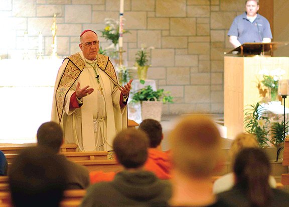 Above, after eucharistic adoration and Benediction at the St. Lawrence Catholic Campus Center in Lawrence, Archbishop Joseph F. Naumann answered questions from the audience during a Trust One Greater event. 
