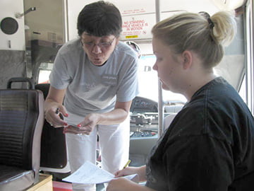 Leaven photo by Sheila Myers Catholic Charities case manager Cindy Gillespie (left) goes over client Darlana Merritt’s paperwork with her inside the resource bus. Gillispie connected Merritt with rent, utility and food assistance using the printer, scanner and Internet-ready computer on the bus.