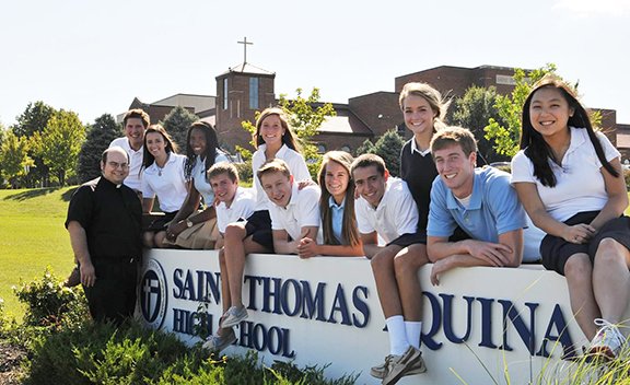 From left to right, Aquinas students Ryan Pottier, Mary Fortino, Lauren Holley, Tyler Heying, Clare Eagan, Jimmy Clark, Katie Ahern, Wade Parks, Margaret Skorija, John Ekedahl, and Theresa Wynne pose with Father Andrew Strobl, chaplain of Aquinas, in front of the school last year. Aquinas was named as a 2012 Blue Ribbon School. Photo by Michelle Gress