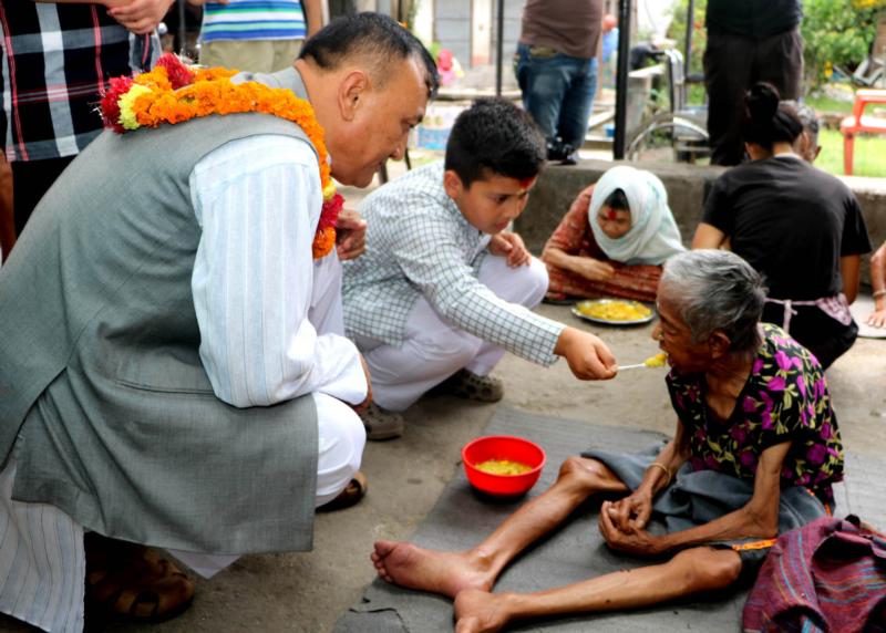 Sanat Kumar Basnet watches his son Bardan celebrate his 11th birthday by feeding an elderly woman at the social welfare center at the Pashupatinath temple in Kathmandu, Nepal, July 4. Inspired by the Missionaries of Charity, many Hindu families volunteer to sponsor food for the people of the destitute home. (CNS photo/Anto Akkara)