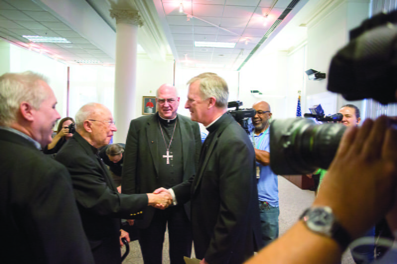 Bishop James Vann Johnston, the new bishop for the Diocese of Kansas City-St. Joseph, greets Msgr. William J. Blacet, pastor of Our Lady of Good Counsel Parish, at a press conference introducing the bishop. Photo by Doug Hesse