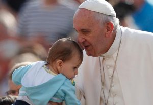 Pope Francis greets a baby during his general audience in St. Peter's Square at the Vatican Oct. 7. The pope said that when families mirror God's love for all, they teach the church how it should relate to all people. (CNS photo/Paul Haring)