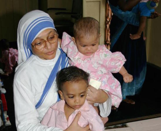 A member of the Missionaries of Charity holds orphan children in 2007 at a center in Kolkata, India. The Missionaries of Charity will close their adoption centers in India, citing new regulations that would allow nontraditional families to adopt children, reported ucanews.com. (CNS photo/Anto Akkara)