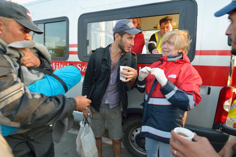 Hungarian volunteers share conversation, Sept. 24, as they give coffee to refugees passing through Hegyeshalom, Hungary, on the way to Austria. (CNS photo/Paul Jeffrey)