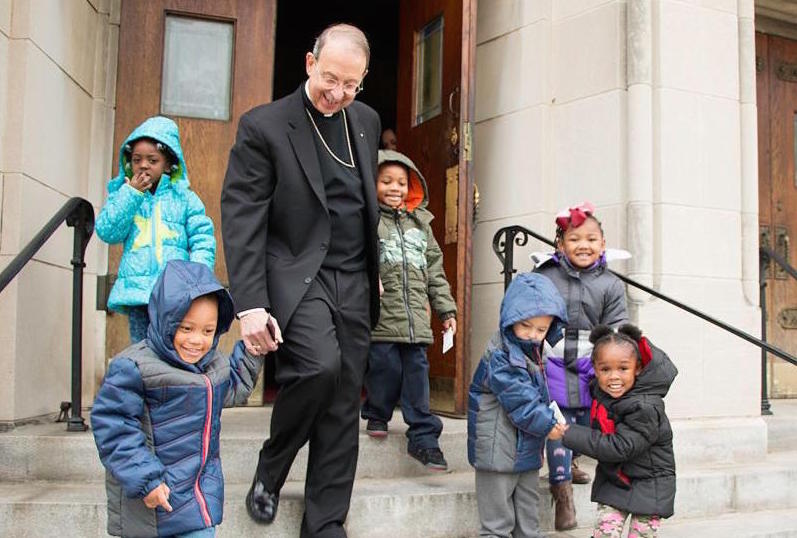 Archbishop William E. Lori of Baltimore walks with children from Catholic Charities Head Start Nov. 30 after helping distribute 1,000 winter coats donated by the Knights of Columbus to neighborhood children at St. Edward in Baltimore. (CNS photo/Olivia Obineme, Catholic Review)
