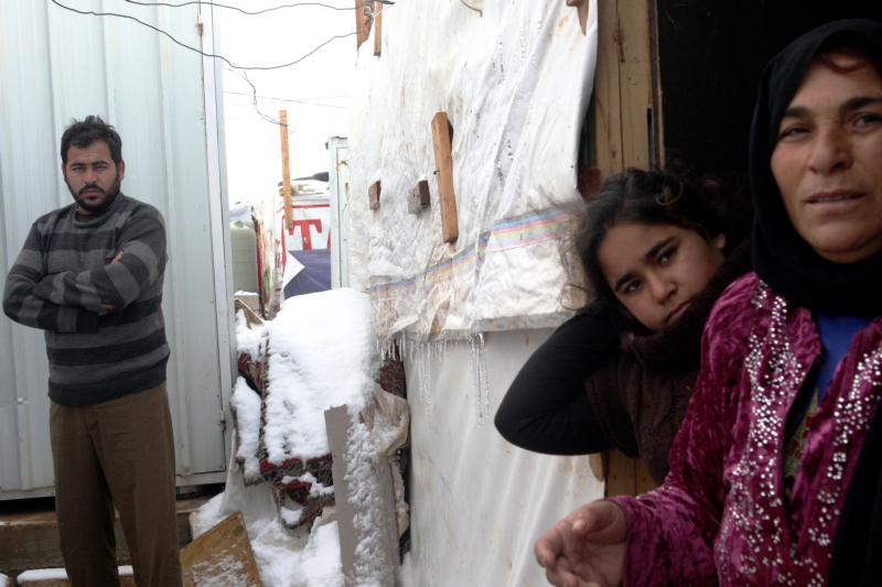 Syrian refugees stand in snow outside their tents Jan. 2 in Lebanon's Bekaa Valley. Lebanon continues to bear the brunt of absorbing massive numbers of refugees. (CNS photo/Lucie Parsaghian, EPA)