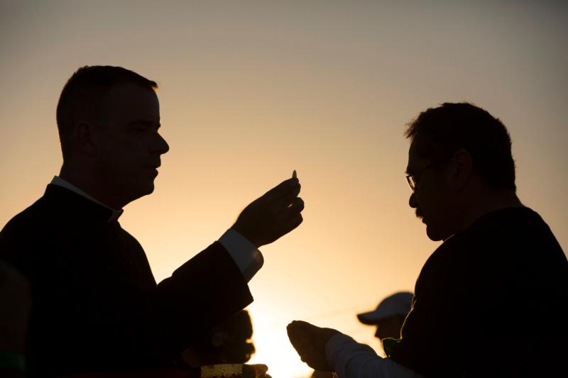 Msgr. J. Brian Bransfield gives Communion to a man attending Mass on the U.S. side of the border in El Paso, Texas, Feb. 17. About 550 guests situated on a levee north of the Rio Grande participated in the Mass Pope Francis celebrated in Ciudad Juarez, Mexico. Msgr. Bransfield is general secretary of the U.S. Conference of Catholic Bishops. (CNS photo/Nancy Wiechec)