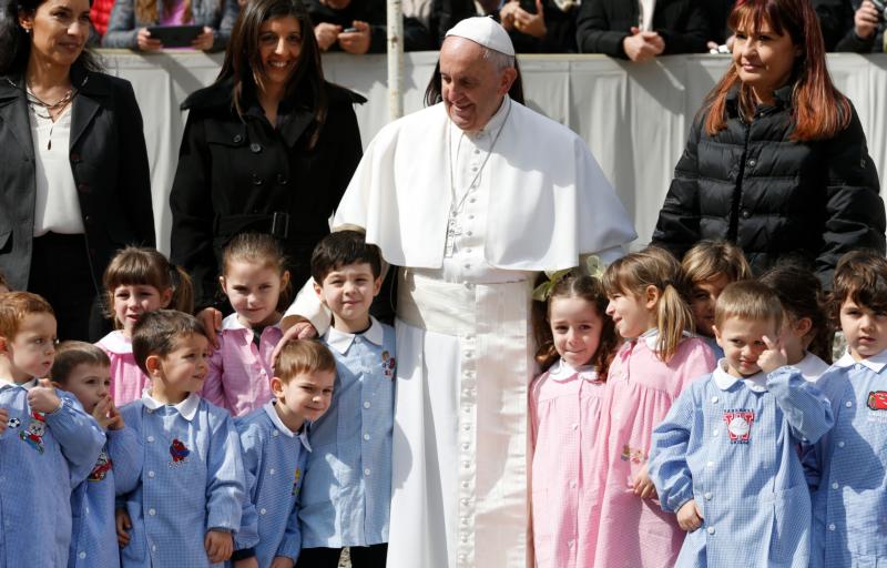 Pope Francis poses with children during his general audience in St. Peter's Square at the Vatican March 16. (CNS photo/Paul Haring)