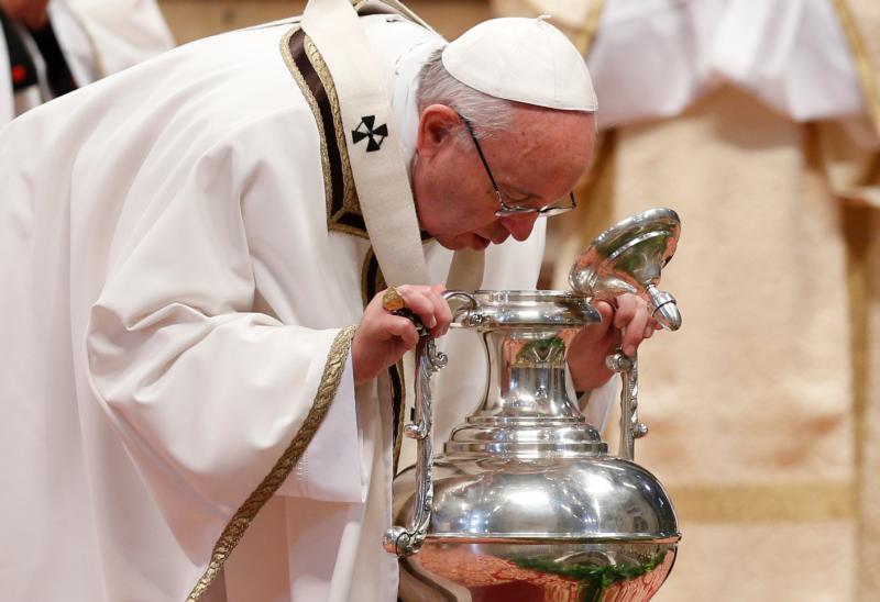 Pope Francis breathes over chrism oil, a gesture symbolizing the infusion of the Holy Spirit, during the Holy Thursday chrism Mass in St. Peter's Basilica at the Vatican March 24. (CNS photo/Paul Haring)