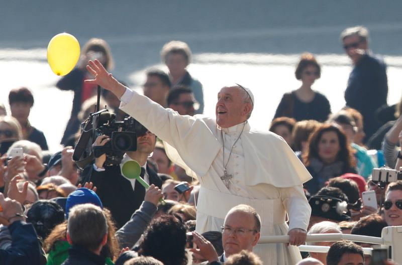 Pope Francis reaches for a balloon released by someone in the crowd during his general audience in St. Peter's Square at the Vatican March 30. The power of God's forgiveness "is greater than our sins," the pope said in his audience talk. (CNS photo/Paul Haring)
