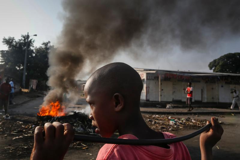 A boy looks on as he holds a stick in front of a burning barricade during a 2015 demonstration in Bujumbura, Burundi, against President Pierre Nkurunziza's bid for a third term. A Catholic aid official urged the government of Burundi not to threaten the church, which he said plays an important role in sustaining society. (CNS photo/Dai Kurokawa, EPA)
