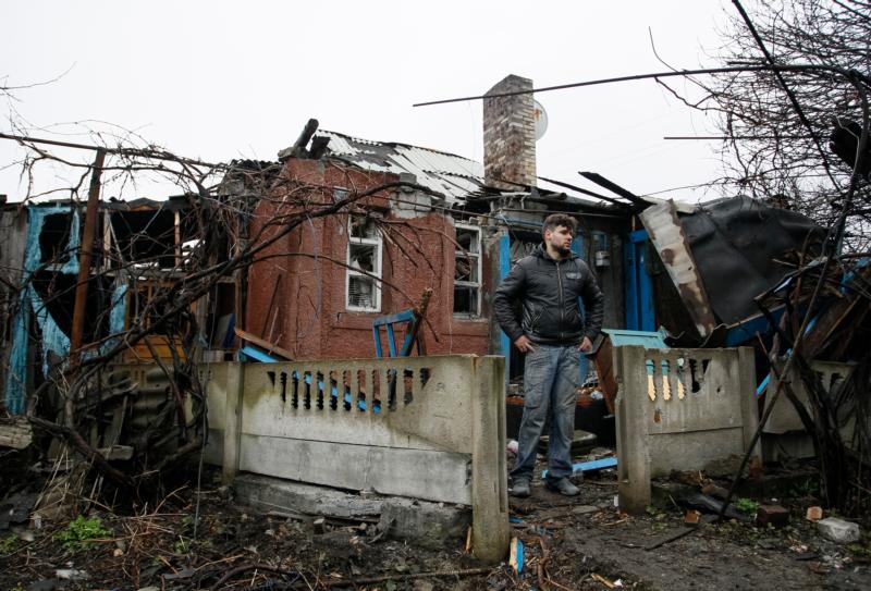 A man stands in front his damaged house after shelling March 24 in the Ukrainian town of Makeevka. (CNS photo/Alexander Ermochenko, EPA)