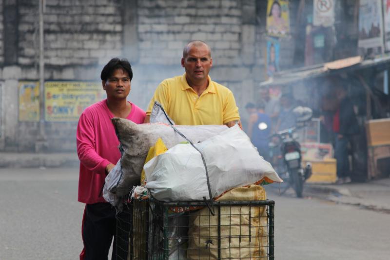 Mark Crosbie walks with Mel Macaereg in Manila, Philippines, in this undated photo. Crosbie, an Irish Catholic street cleaner who was filmed for a job-swap TV documentary, has pledged to spend the rest of his life helping the struggling family he lived with in Manila. (CNS photo/courtesy RTE)