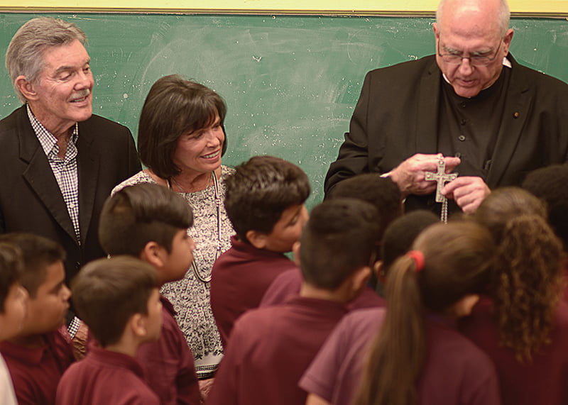 Tom and Sandy Long look on as Archbishop Joseph F. Naumann shows students at Christ the King School in Kansas City, Kansas, the pectoral cross he wears. The Longs are this year’s Angels Among Us honorees for their contributions to Catholic education. LEAVEN PHOTO BY JILL RAGAR ESFELD