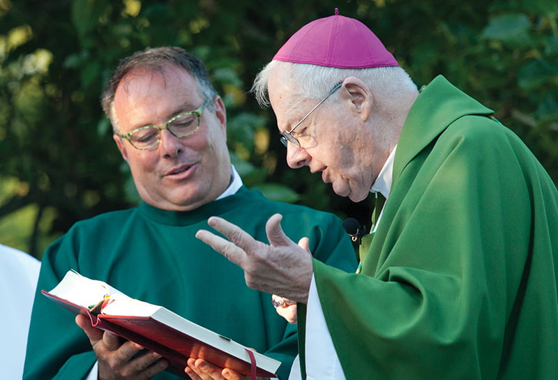 Deacon Dana Nearmyer assists Archbishop Emeritus James P. Keleher at a Mass at Prairie Star Ranch this summer. Deacon Nearmyer was part of the first class of permanent deacons that Archbishop Keleher was responsible for getting started in the archdiocese. LEAVEN PHOTO BY JAY SOLDNER