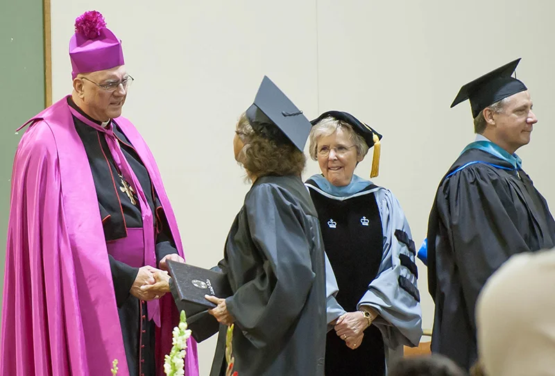 Archbishop Joseph F. Naumann congratulates a graduate of Donnelly College at the graduation ceremony May 9 at the Jack Reardon Civic Center in Kansas City, Kansas, as Sister Anne Shepard, prioress of the Benedictine Sisters in Atchison, looks on. Photo by Jessica Langdon.