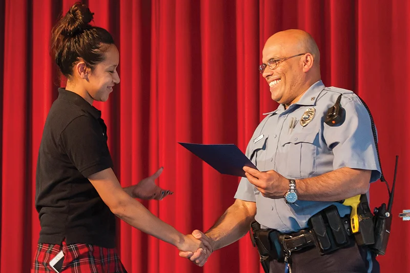 Officer Santiago Vasquez, Bishop Ward student resource officer and a senior master patrolman with the Kansas City, Kansas, Police Department congratulates senior Yusmayra Calderon on completing Ward’s Junior Police Academy program. Photo by Jessica Langdon. 